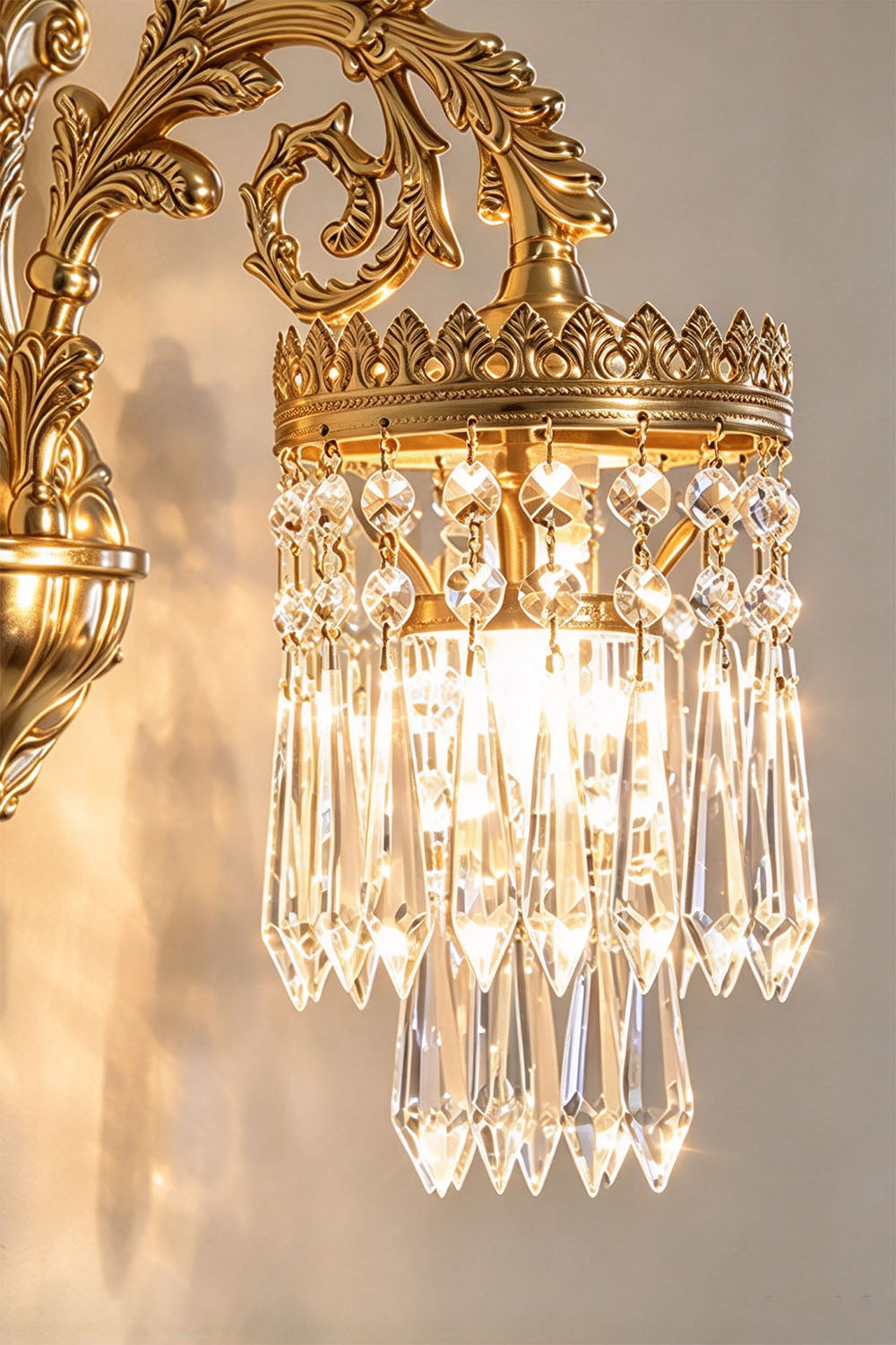 Josseline Brass Crystal Crown Wall Lamp | Cut Crystal and Brass | Close view of the single-arm sconce glowing softly on a textured wall | Samu Lamp