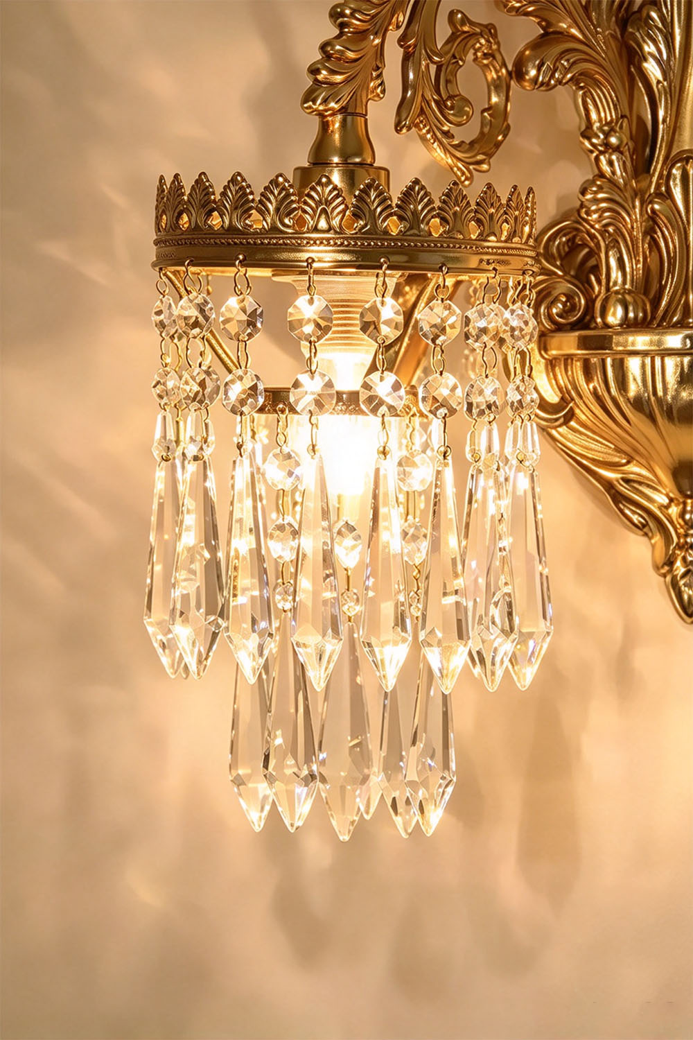 Josseline Brass Crystal Crown Wall Lamp | Cut Crystal and Brass | Close-up detail of the illuminated crystal crown shade and hanging prisms | Samu Lamp