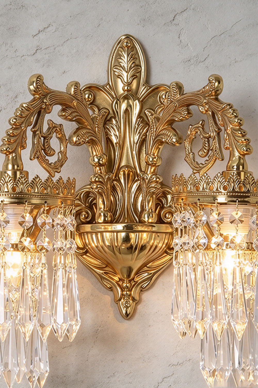 Josseline Brass Crystal Crown Wall Lamp | Cut Crystal and Brass | Close-up view of the carved brass backplate and crystal drops of the double-arm variant | Samu Lamp