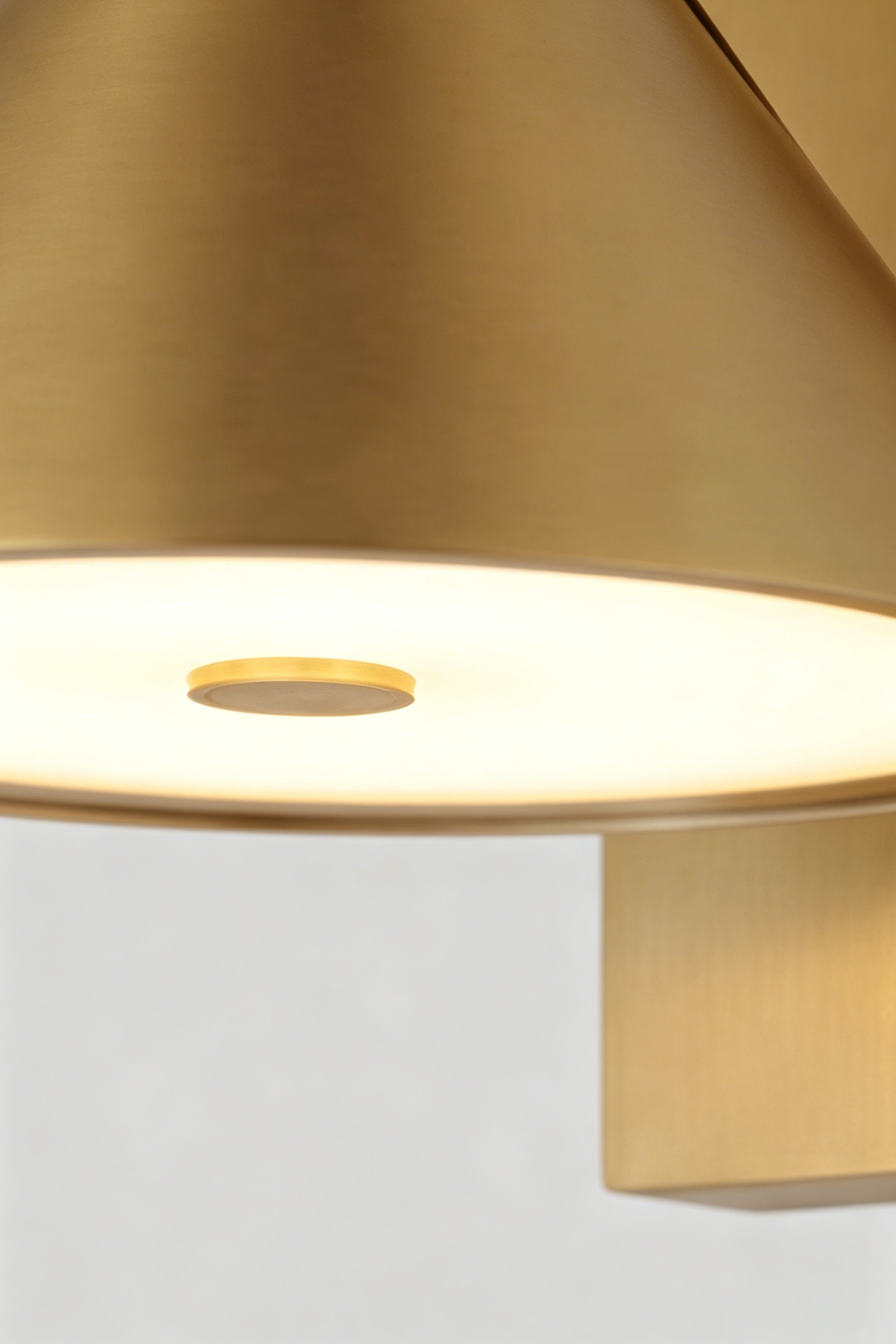Kaelen Brass Cone Wall Sconce | Diffuser Plate Detail | Macro close-up shot looking underneath the glowing conical brass shade highlighting the frosted white integrated led diffuser lens | Detail shot | Samu Lamp