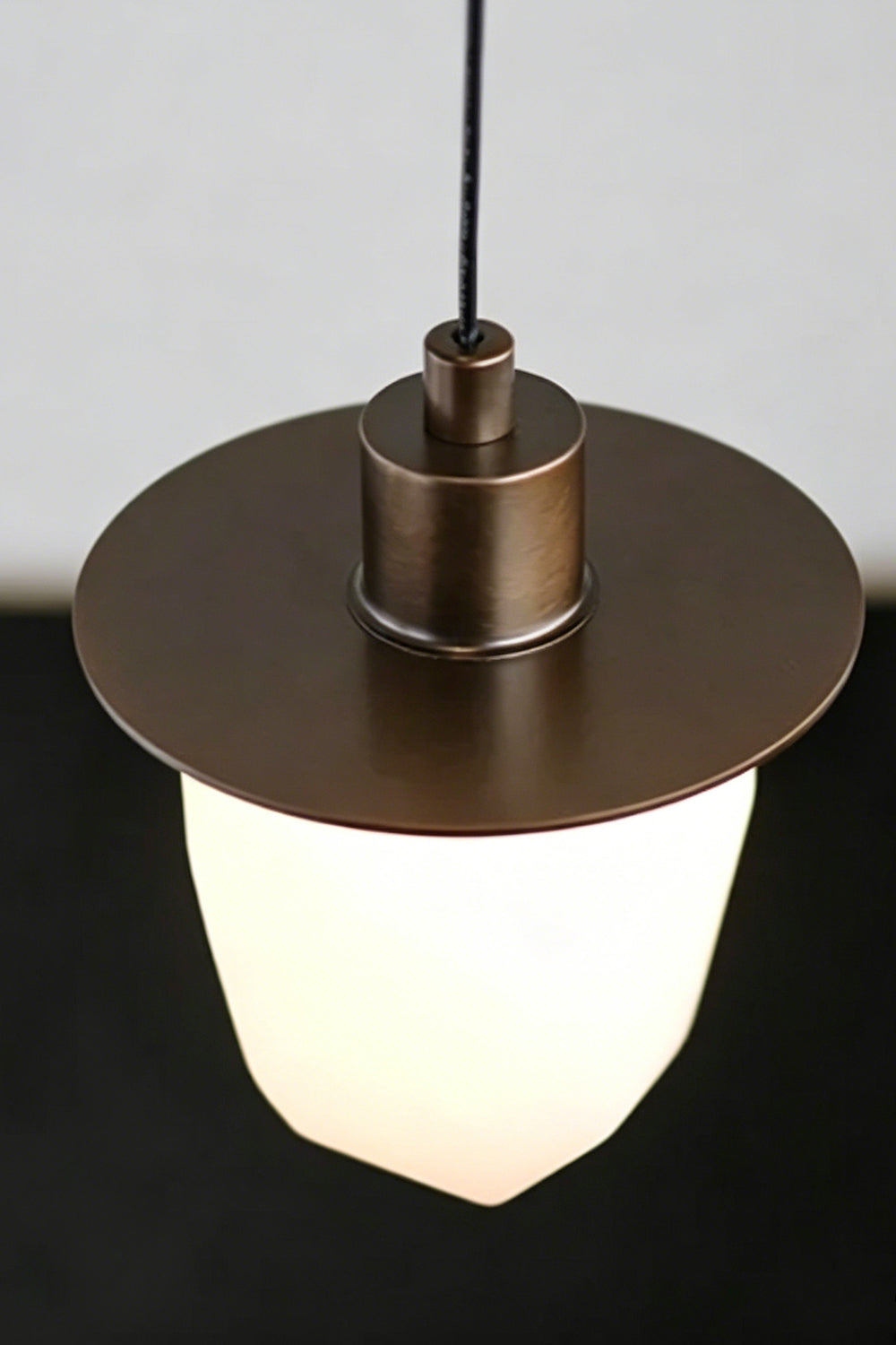 Kaelen Faceted Alabaster Pendant Light | Alabaster, Metal | Close-up focus on the flat dark bronze metal disc brim and hardware neck fixing the glowing translucent stone shade | Detail shot | Samu Lamp