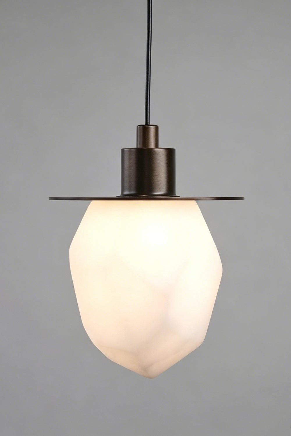 Kaelen Faceted Alabaster Pendant Light | Alabaster, Metal | Close-up studio view of the lit stone lamp highlighting the soft glow transmitting through the natural mineral facets | Detail shot | Samu Lamp