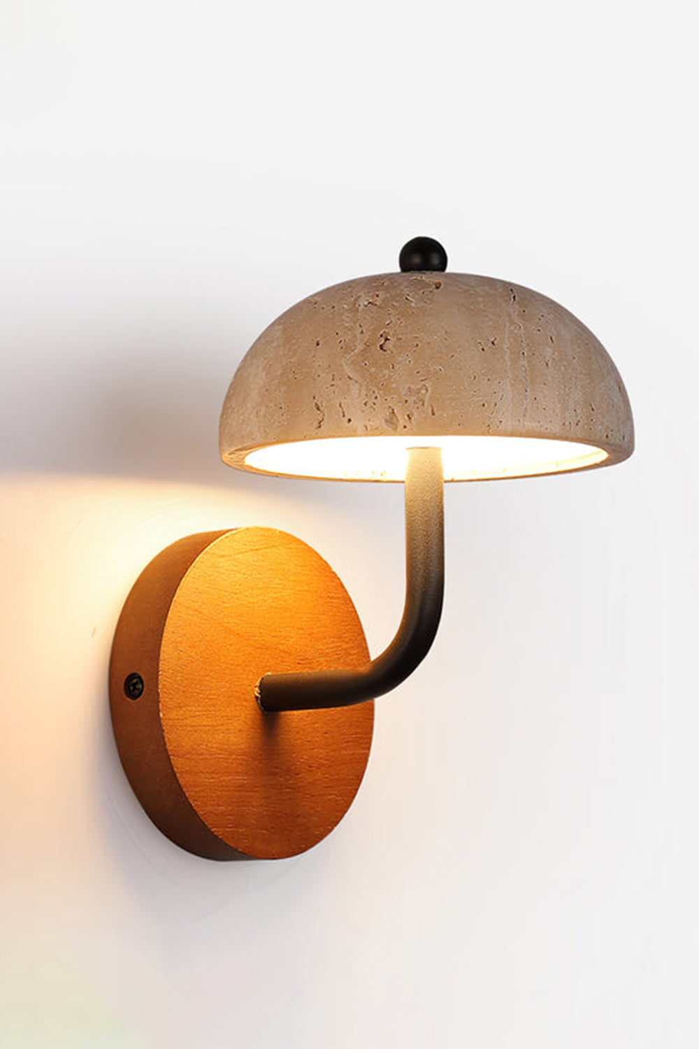 Koba Travertine Mushroom Wall Lamp | Travertine, Wood, Metal | Front view of the fully illuminated stone mushroom sconce casting a soft backlight halo on a plain wall | Samu Lamp