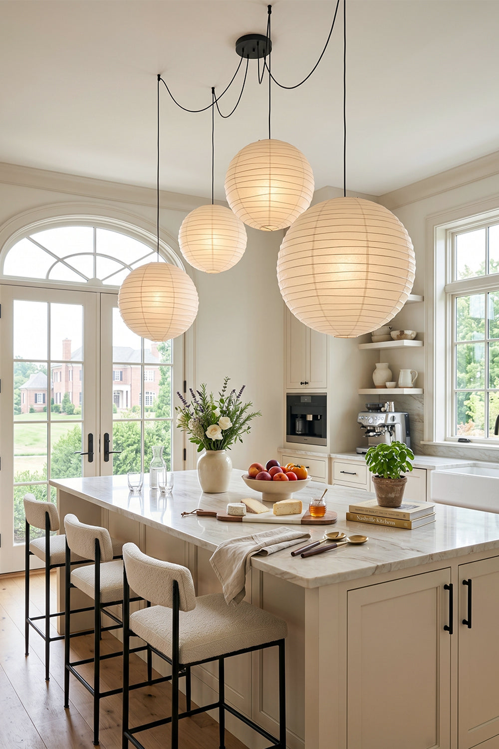 Komorebi Mulberry Paper Pendant Light | Paper, Bamboo | Clustered organic paper lanterns hanging above a pristine white kitchen island counter with black minimalist bar stools | Samu Lamp