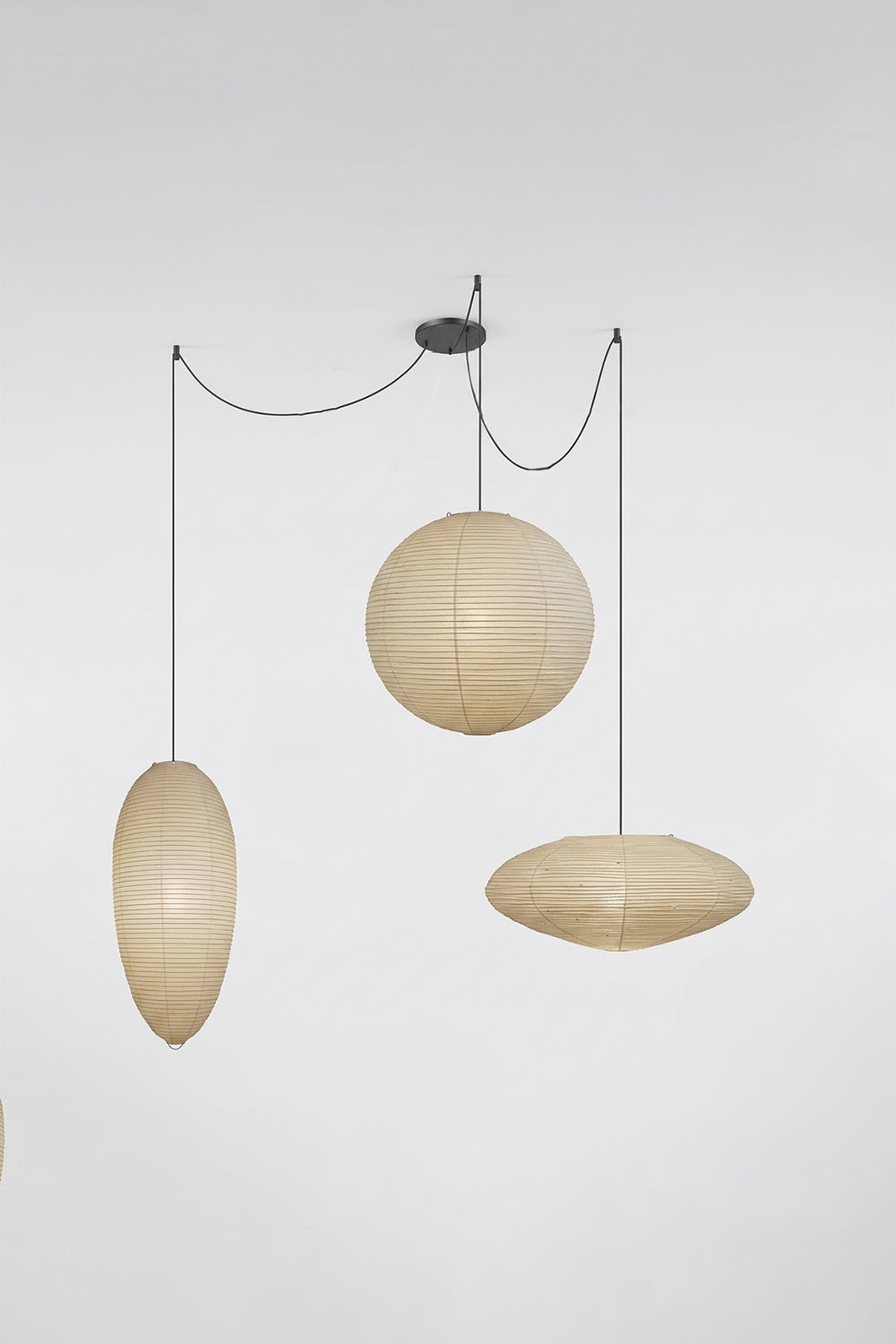 Komorebi Mulberry Paper Pendant Light | Paper, Bamboo | Studio view of an unlit 3-light combination variant featuring an oval, sphere, and saucer shade on black cords | Samu Lamp