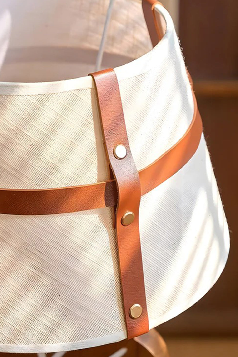 Leafora Botanical Leaf Table Light | Wood, Fabric, Leather | Close-up focus on the cream woven fabric lampshade highlighting the detailed brown leather intersecting straps and metal rivet button | Detail shot | Samu Lamp