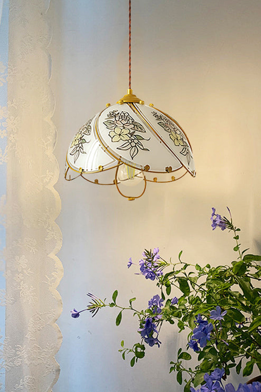 Lillian Retro Floral Pendant Lamp | Glass, Metal | Casting a warm amber glow next to a delicate white lace curtain with blooming purple flowers below | Samu Lamp