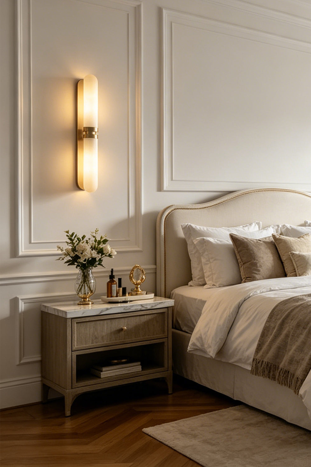 Linea Alabaster Capsule Wall Sconce | Alabaster, Brass | Mounted as a cozy bedtime reading light above a wooden nightstand in a serene classical bedroom | Samu Lamp