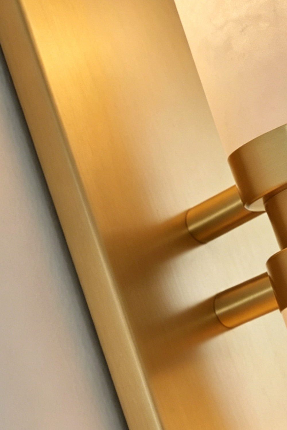 Linea Alabaster Capsule Wall Sconce | Alabaster, Brass | Macro close-up focus on the premium brushed gold brass metallic backing and mount hardware | Detail shot | Samu Lamp