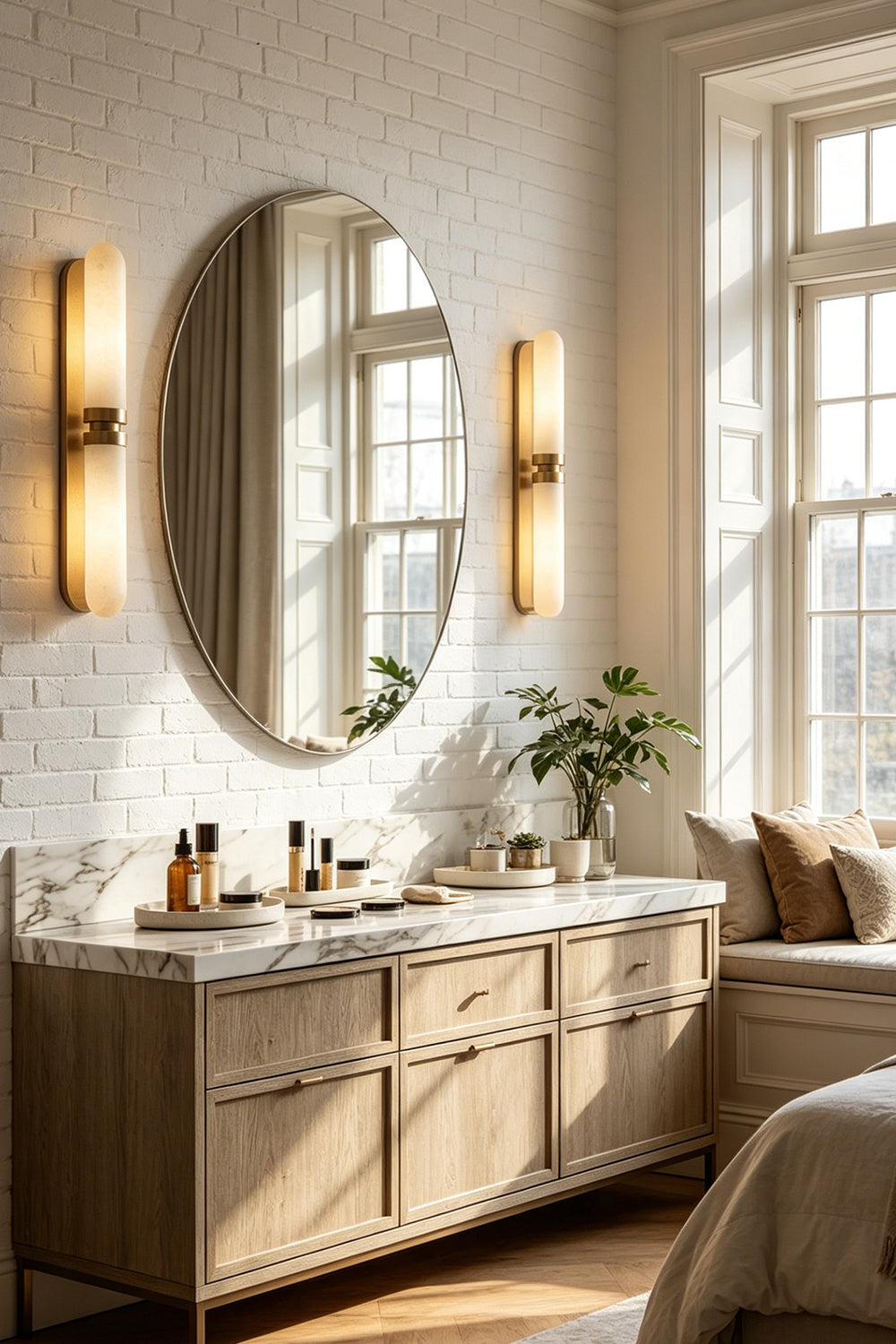 Linea Alabaster Capsule Wall Sconce | Alabaster, Brass | A pair of fully illuminated capsule wall lights flanking a large round mirror in a luxury bathroom vanity setup | Samu Lamp