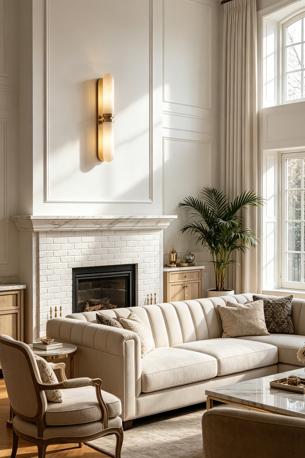 Linea Alabaster Capsule Wall Sconce | Alabaster, Brass | Installed as an elegant wall accent lamp next to a classical fireplace mantle in a bright luxury living room | Samu Lamp