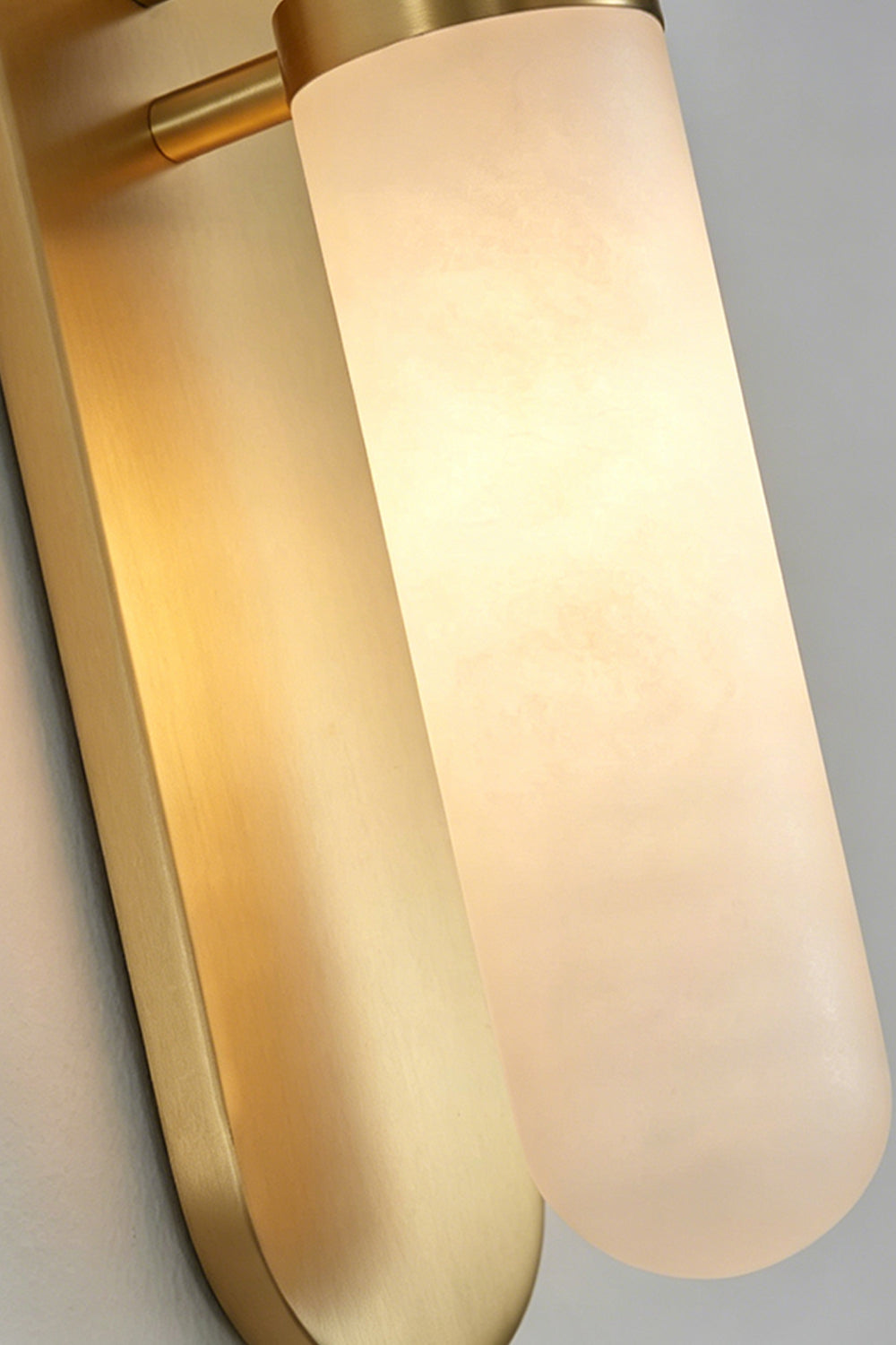 Linea Alabaster Capsule Wall Sconce | Alabaster, Brass | Close-up shot of the illuminated capsule wall fixture showcasing the translucent crystalline texture of natural alabaster | Detail shot | Samu Lamp