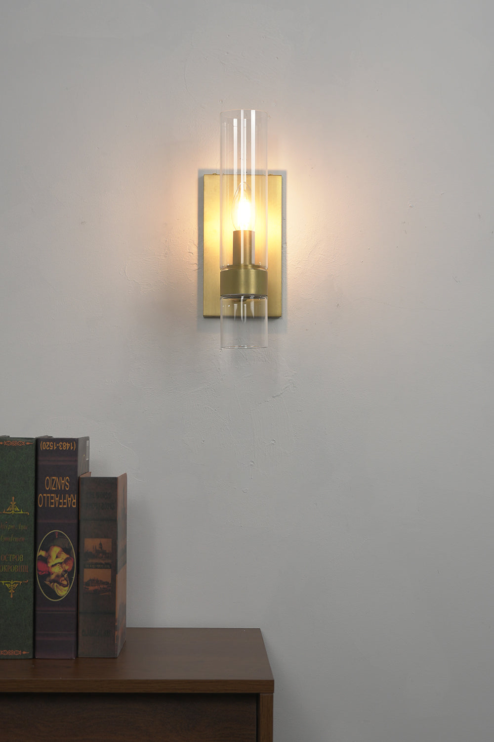 Linear metallic brass sconce lit | Brass, Glass | Positioned above a dark wooden cabinet | Samu Lamp