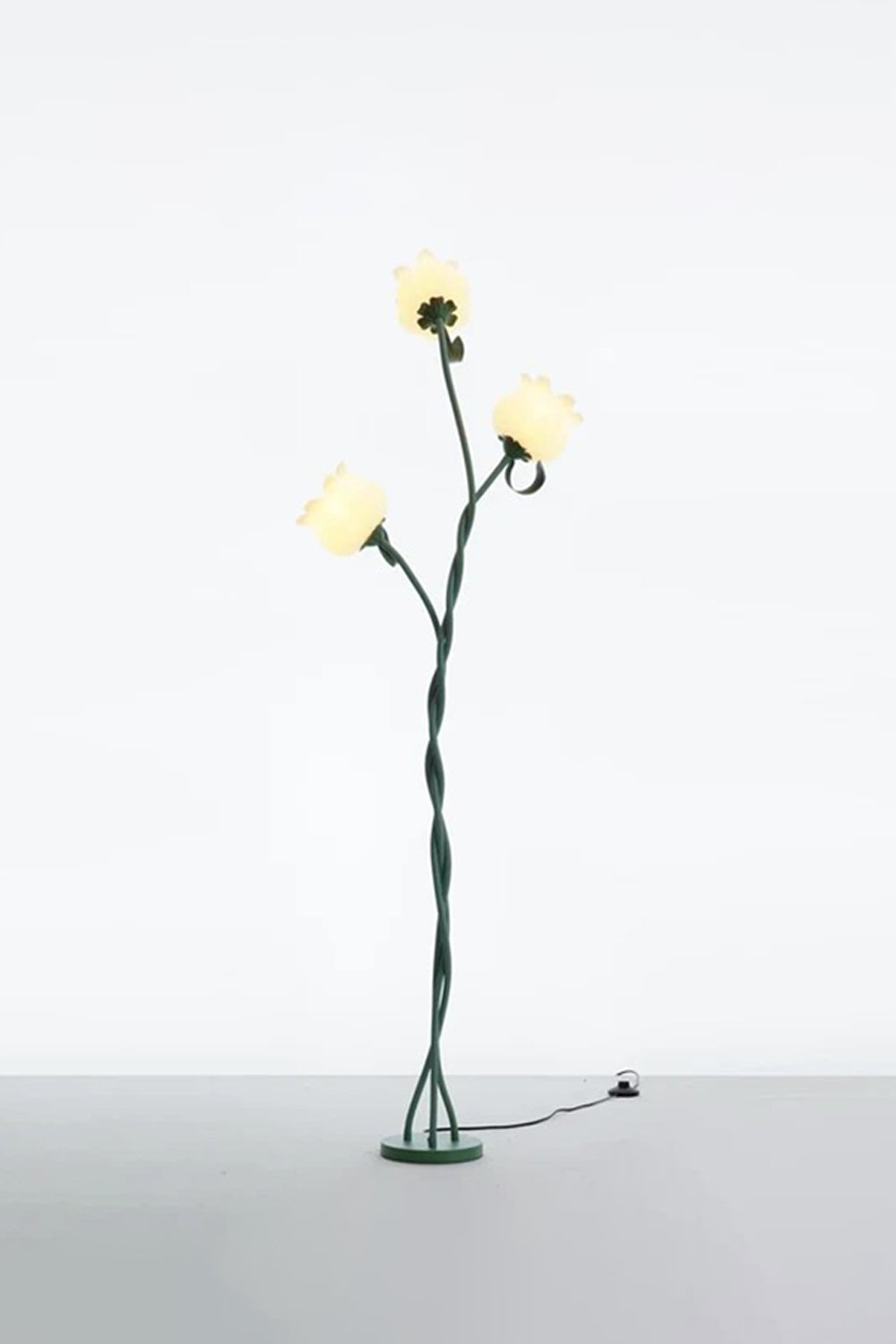 Linnea Tulip Bloom Floor Lamp | Glass and Green Metal | Full standing view glowing softly in a studio setting against a plain wall | Samu Lamp