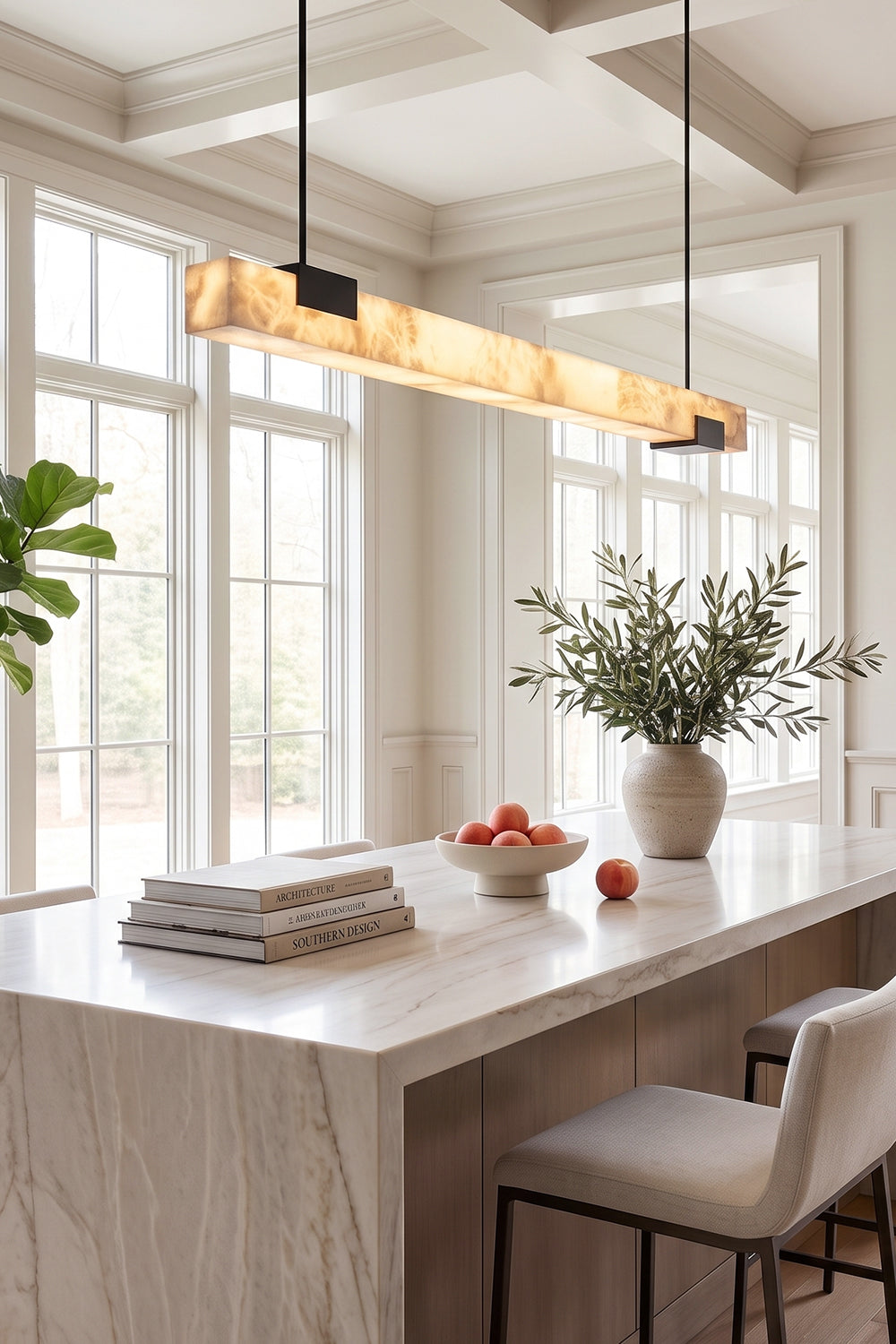Liora Linear Alabaster Pendant Light | Natural Alabaster and Black Metal | Illuminating a modern white marble kitchen island bar counter with high ceiling windows | Samu Lamp