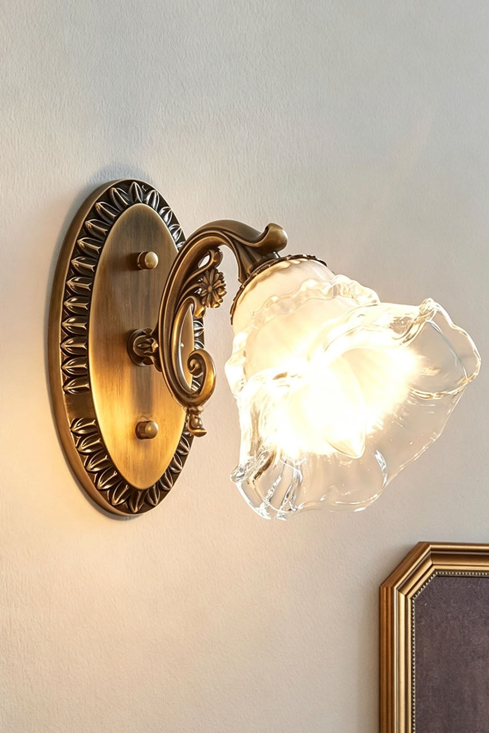 Lisette Blossom Glass Brass Wall Lamp | Glass and Brass | Side angled illuminated view glowing warmly against a plain wall | Samu Lamp