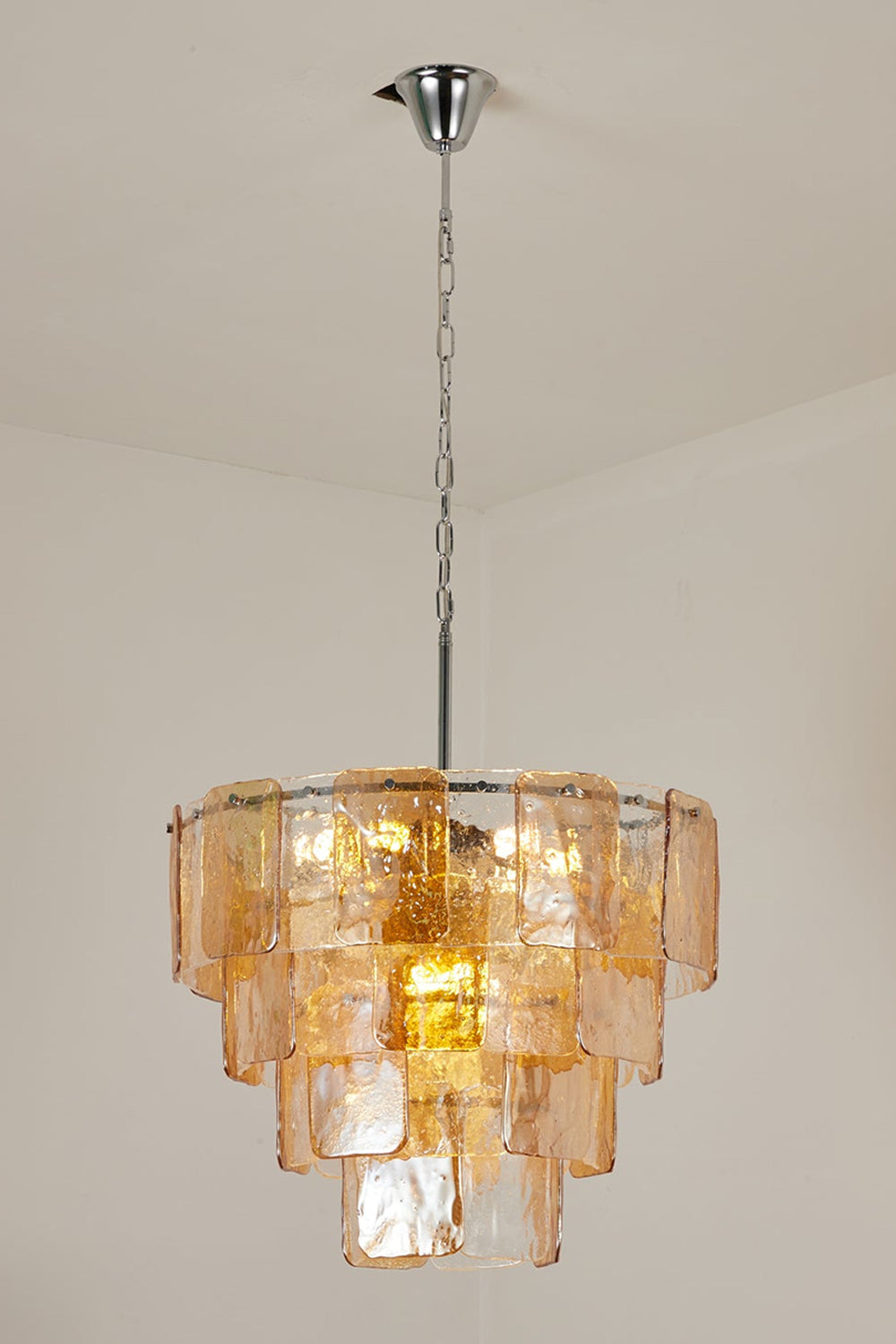 Lucia Tiered Amber Glass Chandelier | Glass, Metal | Studio variant view of a narrower tiered version of the amber glass chandelier illuminated against a plain background | Samu Lamp