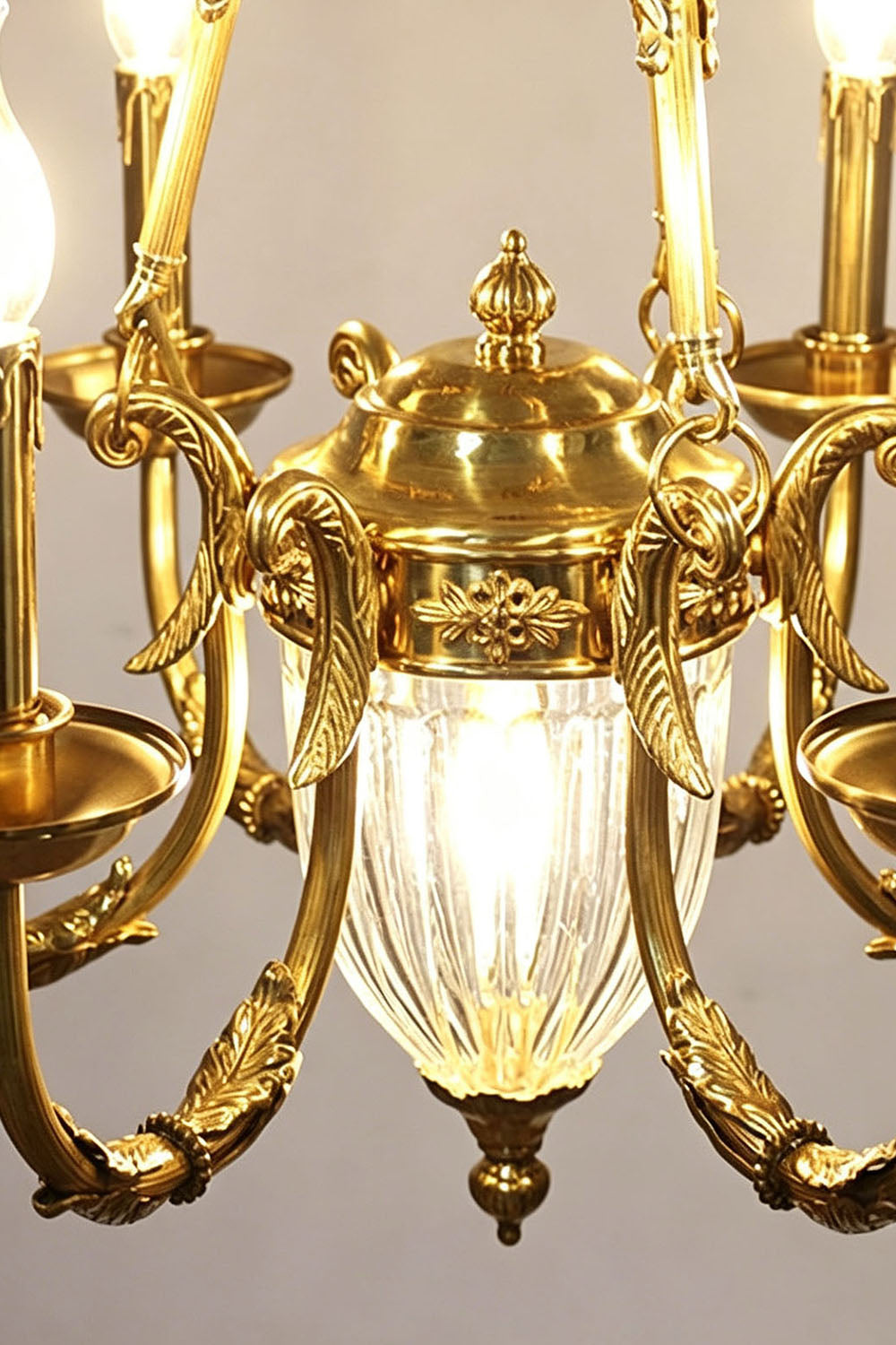 Lucienne Fluted Glass Urn Brass Chandelier featuring elegant gold detailing and illuminated fluted glass accents.