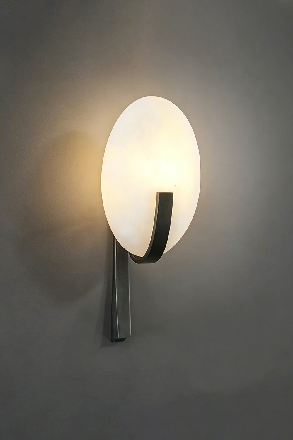 Lunar Veil lamp with warm illumination | Side perspective on dark textured wall | Emphasizing diffused light pattern | Samu Lamp