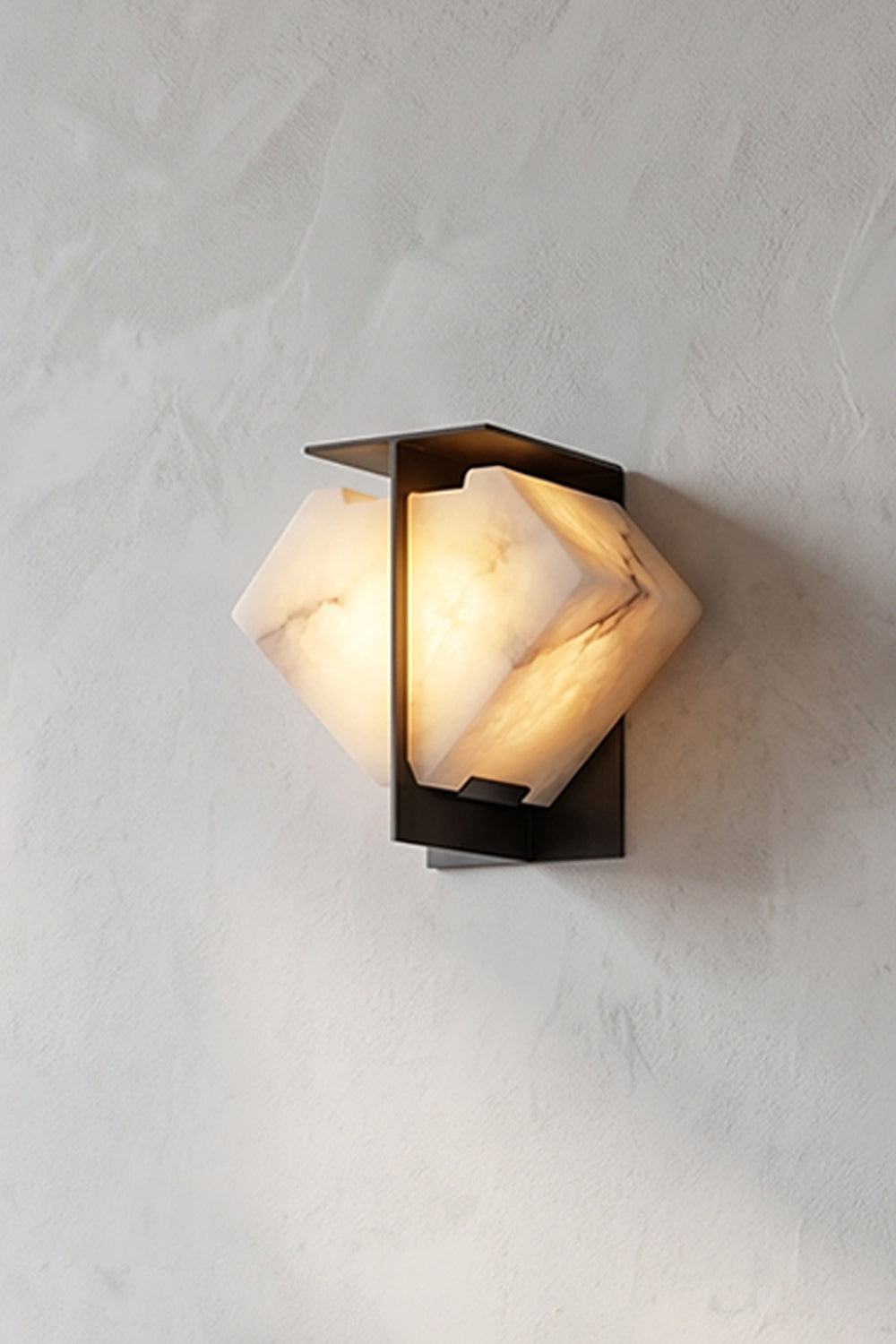 Lysandra Alabaster Folded Halo Wall Lamp | Angle Profile View | Side angle shot of the lit architectural stone wall light highlighting the cloudy natural mineral textures on a plaster wall | Samu Lamp