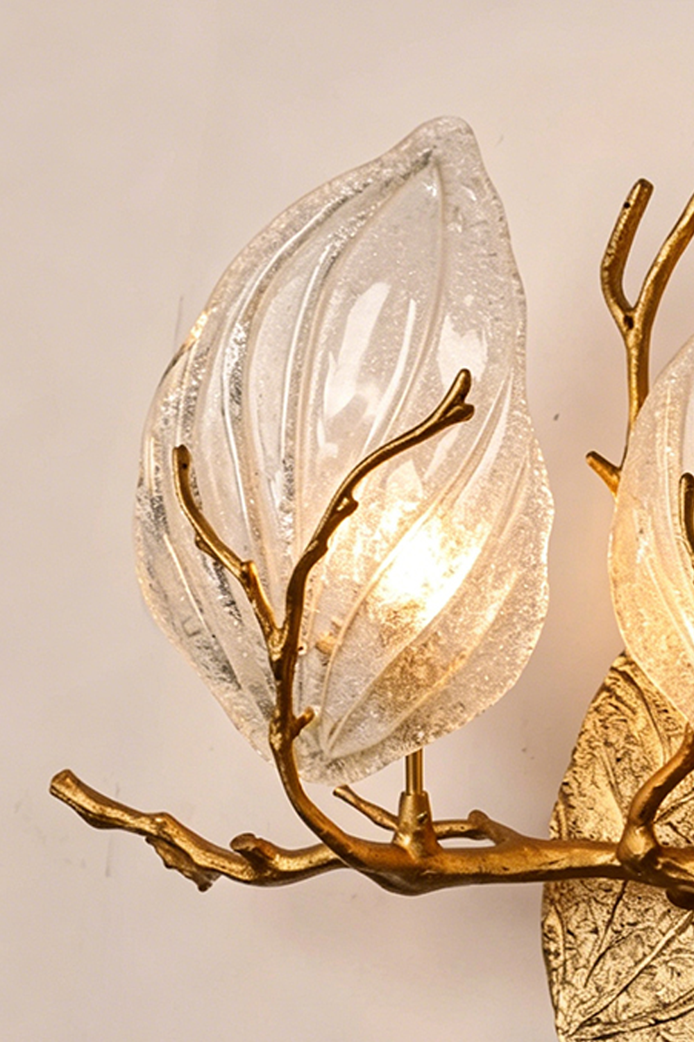 Magnolia Arbor Brass Wall Lamp | Brass, Glass | Close-up focus on the illuminated leaf-shaped clear glass shade and lifelike golden twig | Detail shot | Samu Lamp
