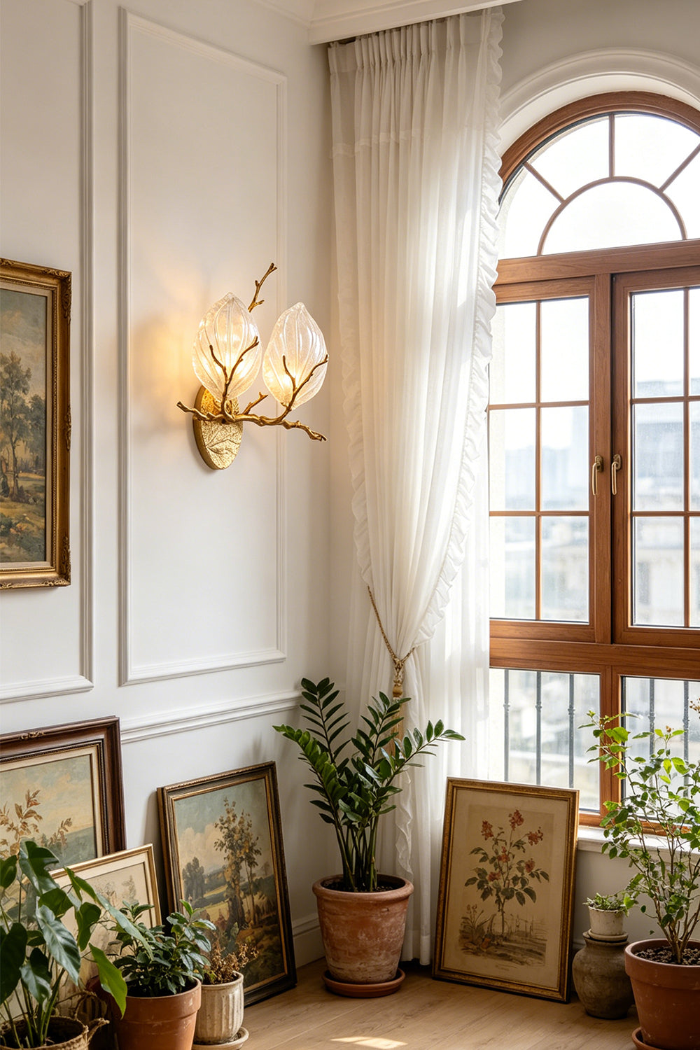 Magnolia Arbor Brass Wall Lamp | Brass, Glass | Illuminating a bright room corner filled with green potted plants and leaning artwork frames | Samu Lamp