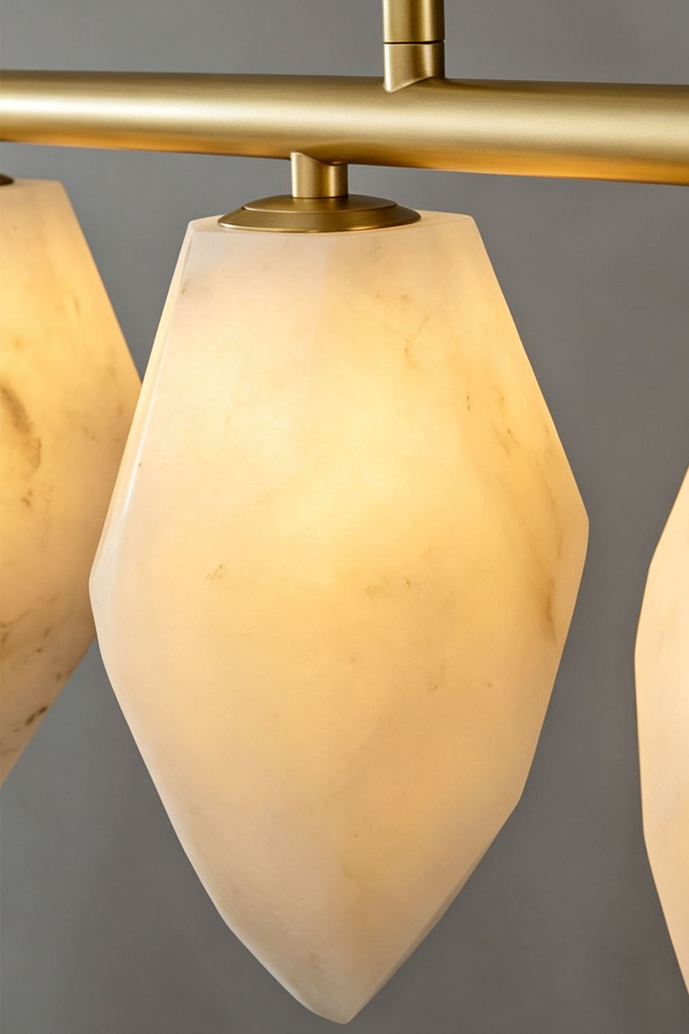 Manon Alabaster Drop Linear Chandelier | Natural Alabaster and Brass | Close-up detail of a single illuminated teardrop alabaster shade | Samu Lamp