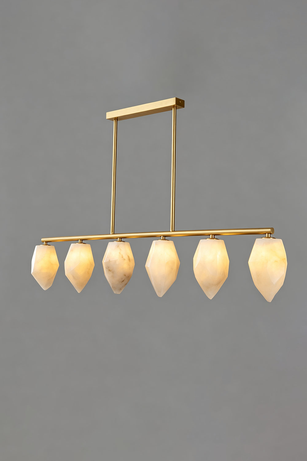 Manon Alabaster Drop Linear Chandelier | Natural Alabaster and Brass | Full front view glowing softly against a solid grey background | Samu Lamp