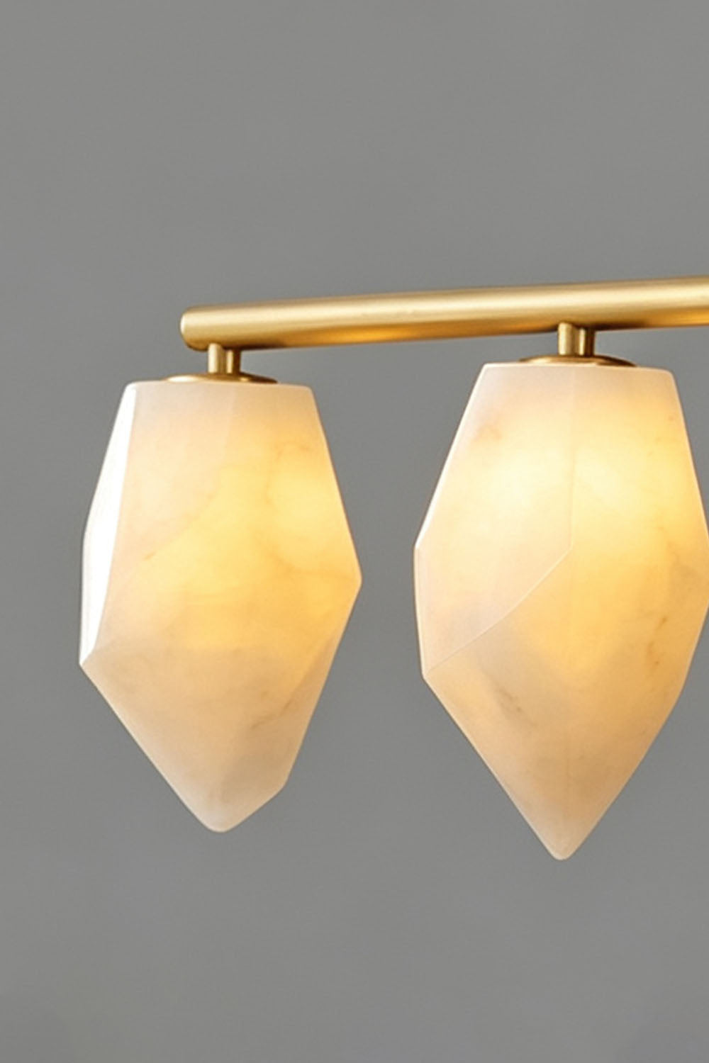 Manon Alabaster Drop Linear Chandelier | Natural Alabaster and Brass | Medium close-up showing two glowing alabaster drop shades against a dark backdrop | Samu Lamp