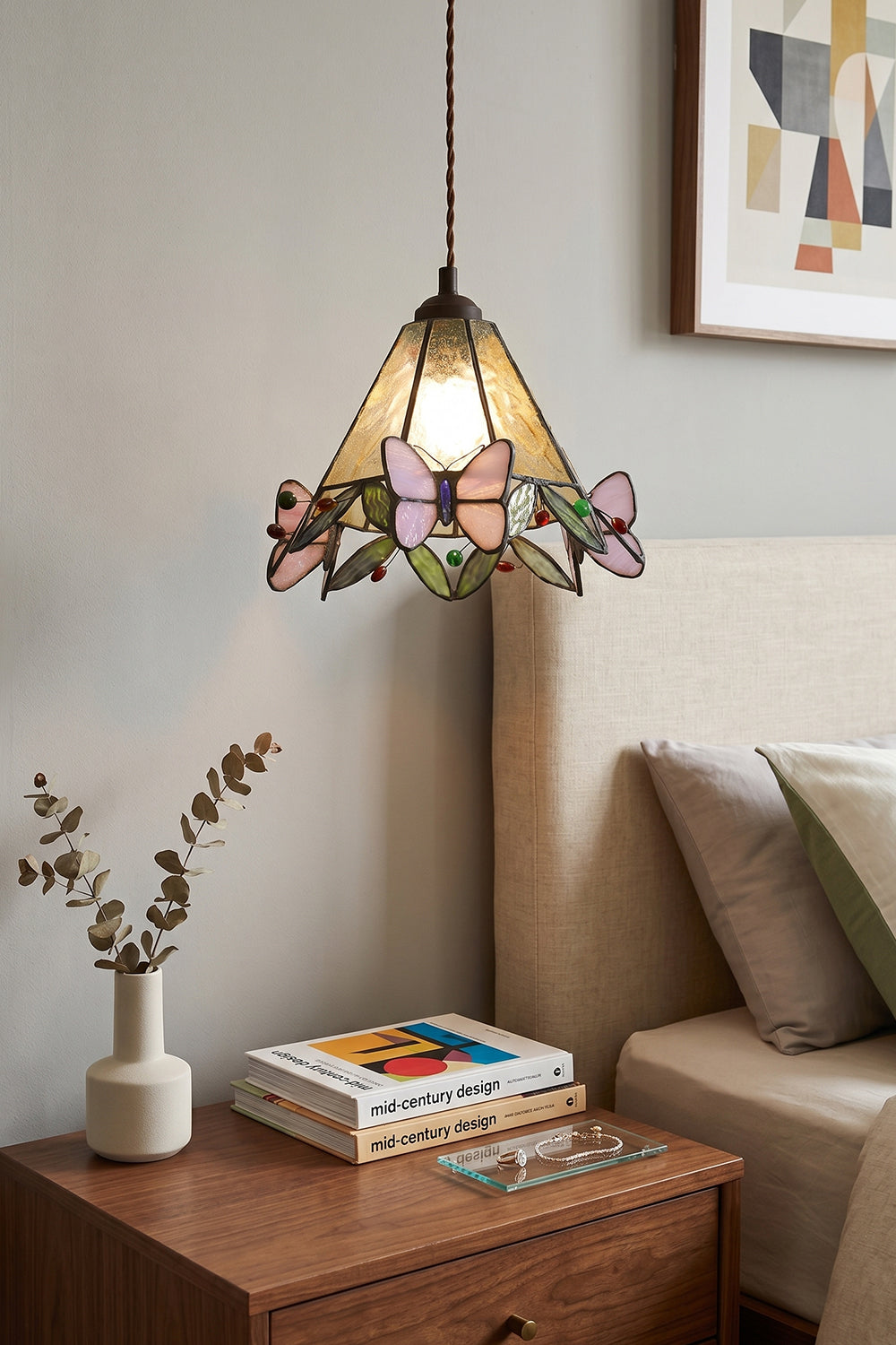 Mariposa Canopy Stained Glass Pendant Lamp | Glass, Metal | Positioned as a warm bedside pendant light over a wooden nightstand with books next to a upholstered bed | Samu Lamp