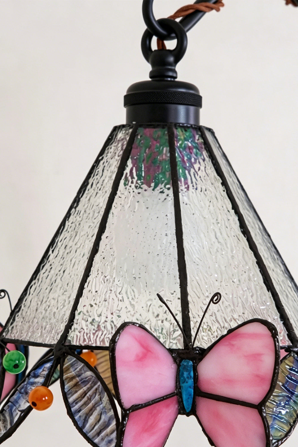 Mariposa Stained Glass Table Lamp | Glass, Metal | Close-up view of the unlit conical stained glass shade with intricate leading and pink butterfly trim | Detail shot | Samu Lamp