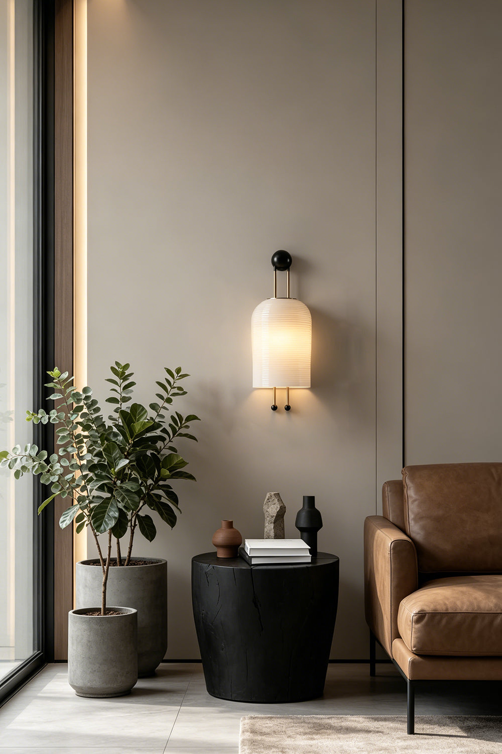 Marlow Linear Ribbed Glass Wall Lamp | Glass, Metal | Illuminating a contemporary lounge corner next to a sleek black side table and a large indoor potted plant | Samu Lamp