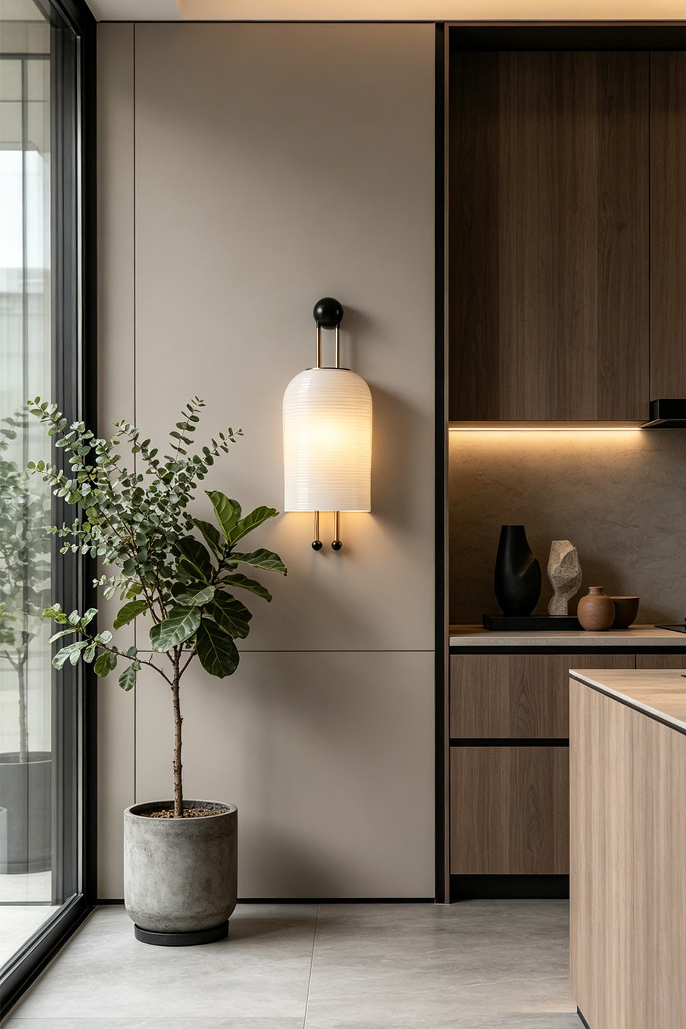 Marlow Linear Ribbed Glass Wall Lamp | Glass, Metal | Wall-mounted in a minimalist room transition corner near modern dark wood kitchen cabinetry and a potted tree | Samu Lamp