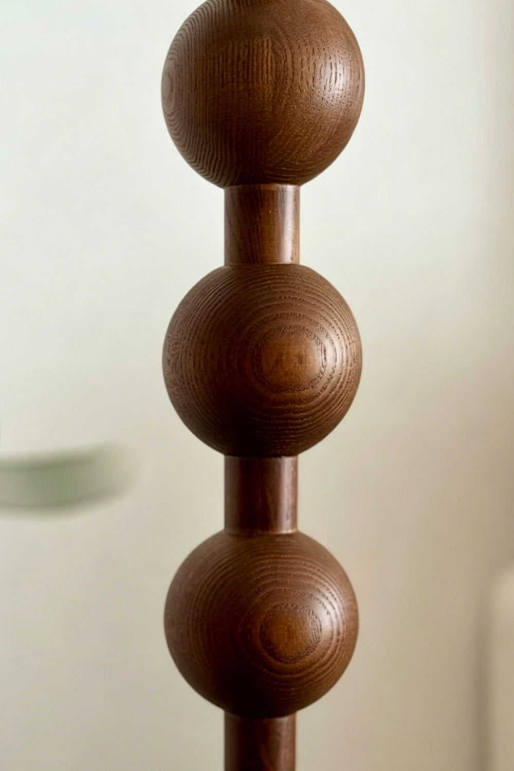 Marlow Stacked Wood Floor Lamp | Wood, Fabric | Close-up macro focus on the carved dark wood stem, showcasing the stacked spherical bobbin design and rich wood grain texture | Detail shot | Samu Lamp