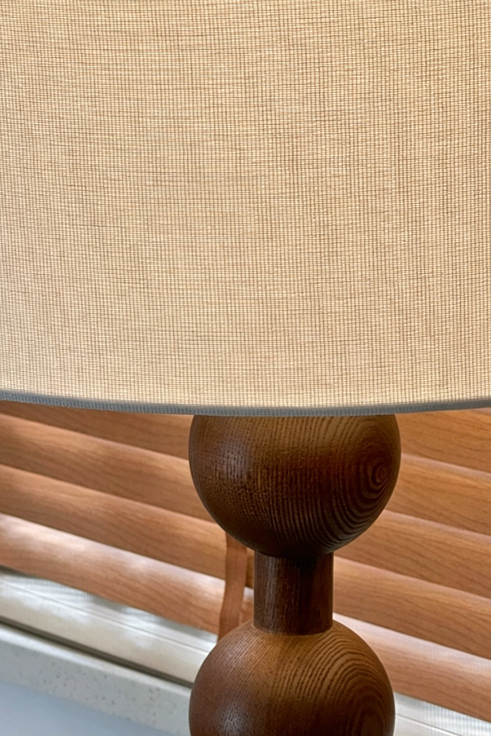 Marlow Stacked Wood Floor Lamp | Wood, Fabric | Detailed close-up view highlighting the textured beige linen drum lampshade meeting the top dark walnut wooden sphere | Detail shot | Samu Lamp
