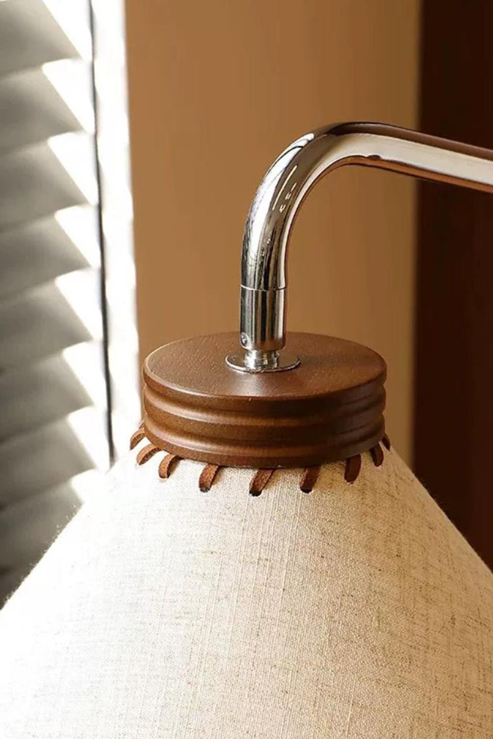 Marlowe Angled Linen Reading Floor Lamp | Linen, Wood, and Chrome Metal | Extreme close-up shot of the curved chrome pipe neck inserting into the dark wood trim atop the shade | Samu Lamp