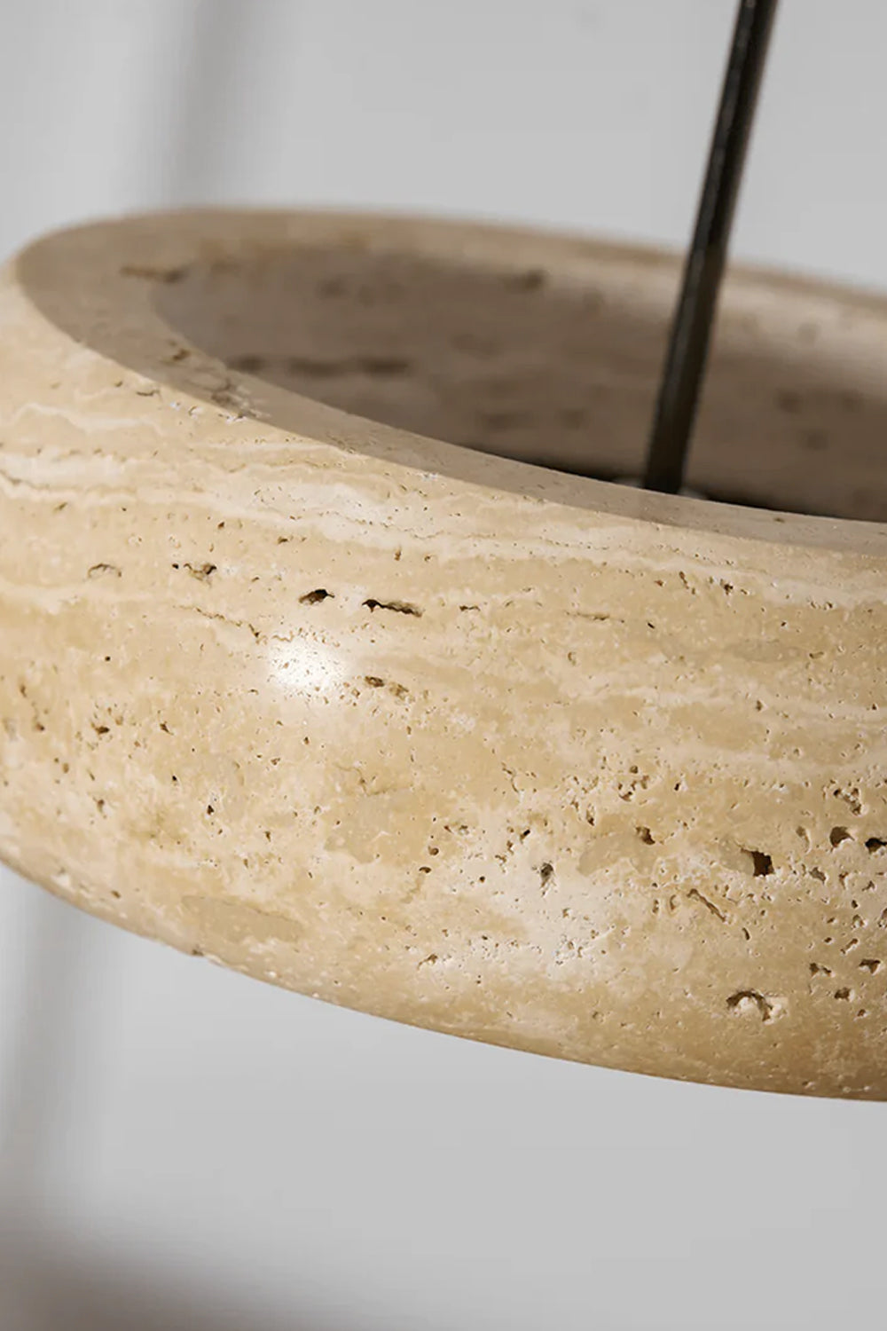 Maro Travertine Donut Pendant Light | Travertine, Metal | Close-up top angled shot of the unlit natural cream travertine stone body showcasing its organic earthy details and cord entry | Detail shot | Samu Lamp
