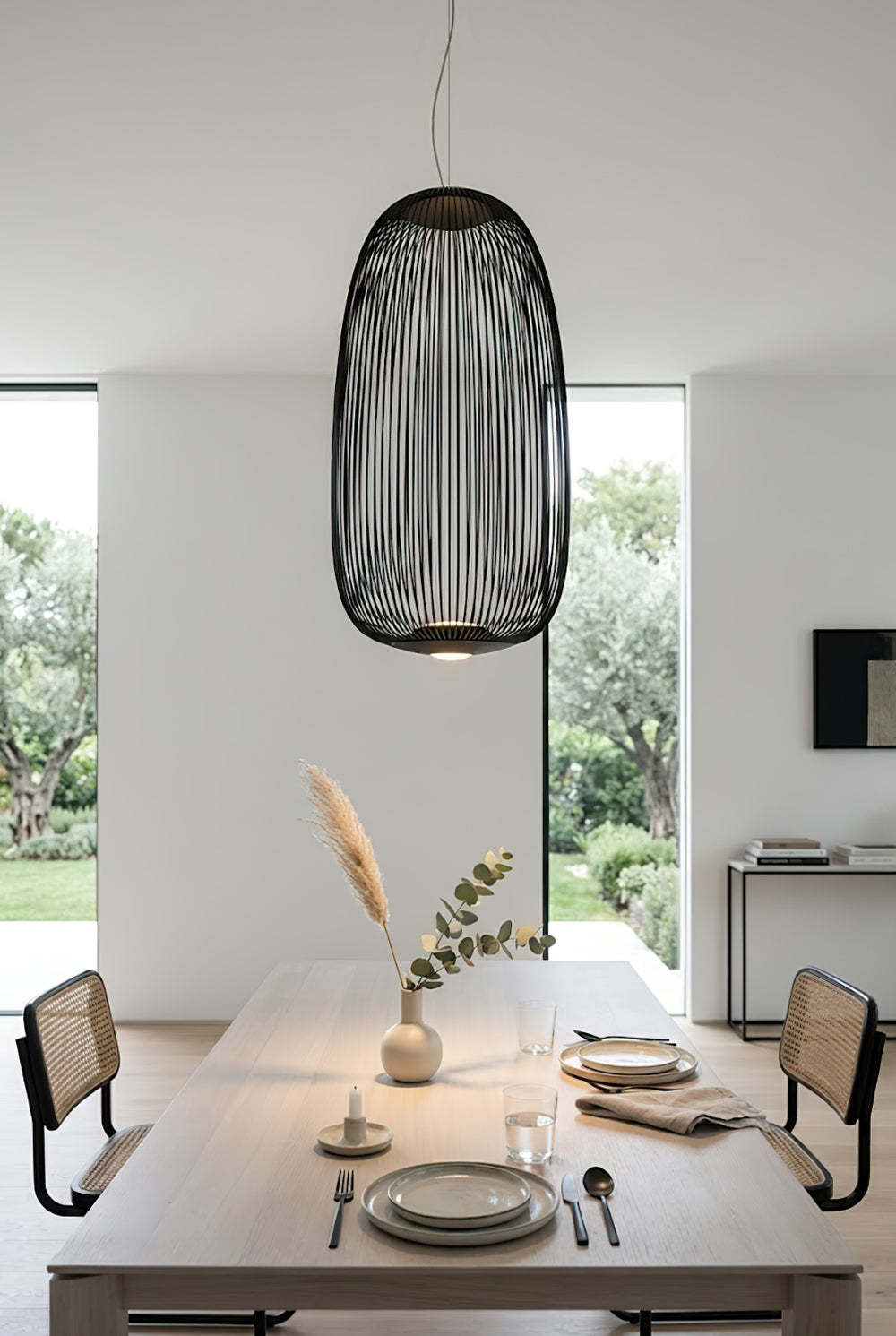 Black wire cage pendant over long dining table | Aluminum | Spacious interior scene with modern chairs | Samu Lamp