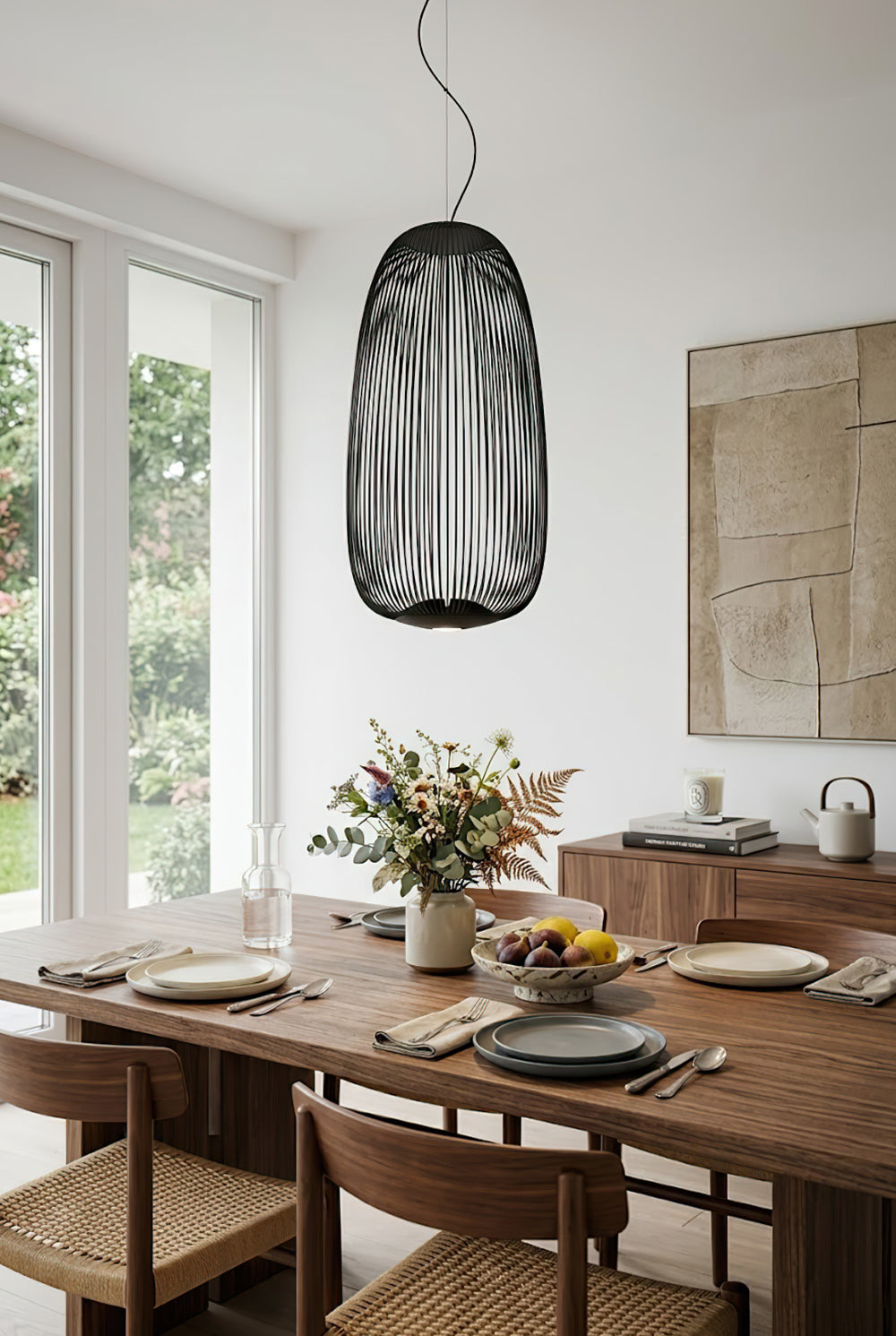 Black elliptical wire cage lamp in dining room | Aluminum | Over a wooden table with chairs and plants | Samu Lamp