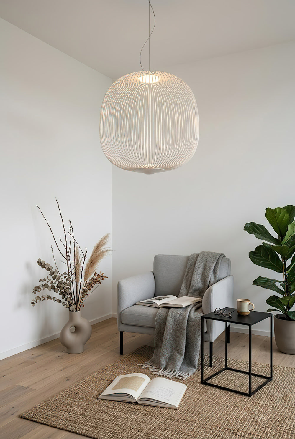 White wire cage pendant light over a reading chair | Aluminum | Cozy corner scene with a grey armchair | Samu Lamp