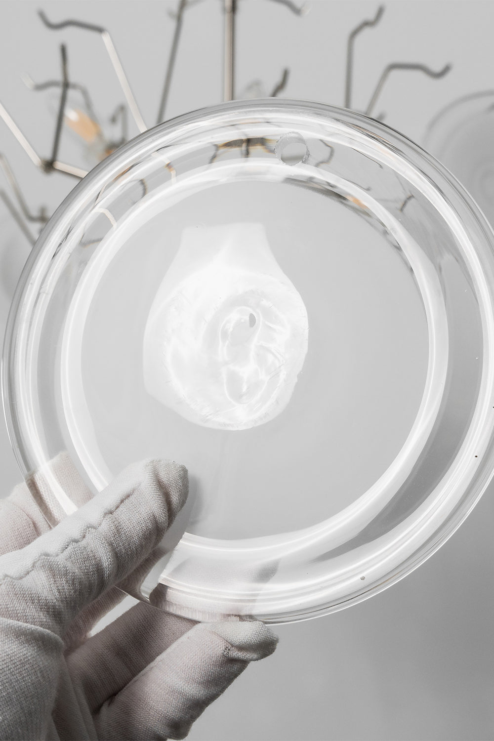 Mirella Circular Glass Pane Ceiling Light | Glass Pane Detail | Close-up shot showing a white-gloved hand holding an individual circular frosted white glass disc plate component | Detail shot | Samu Lamp