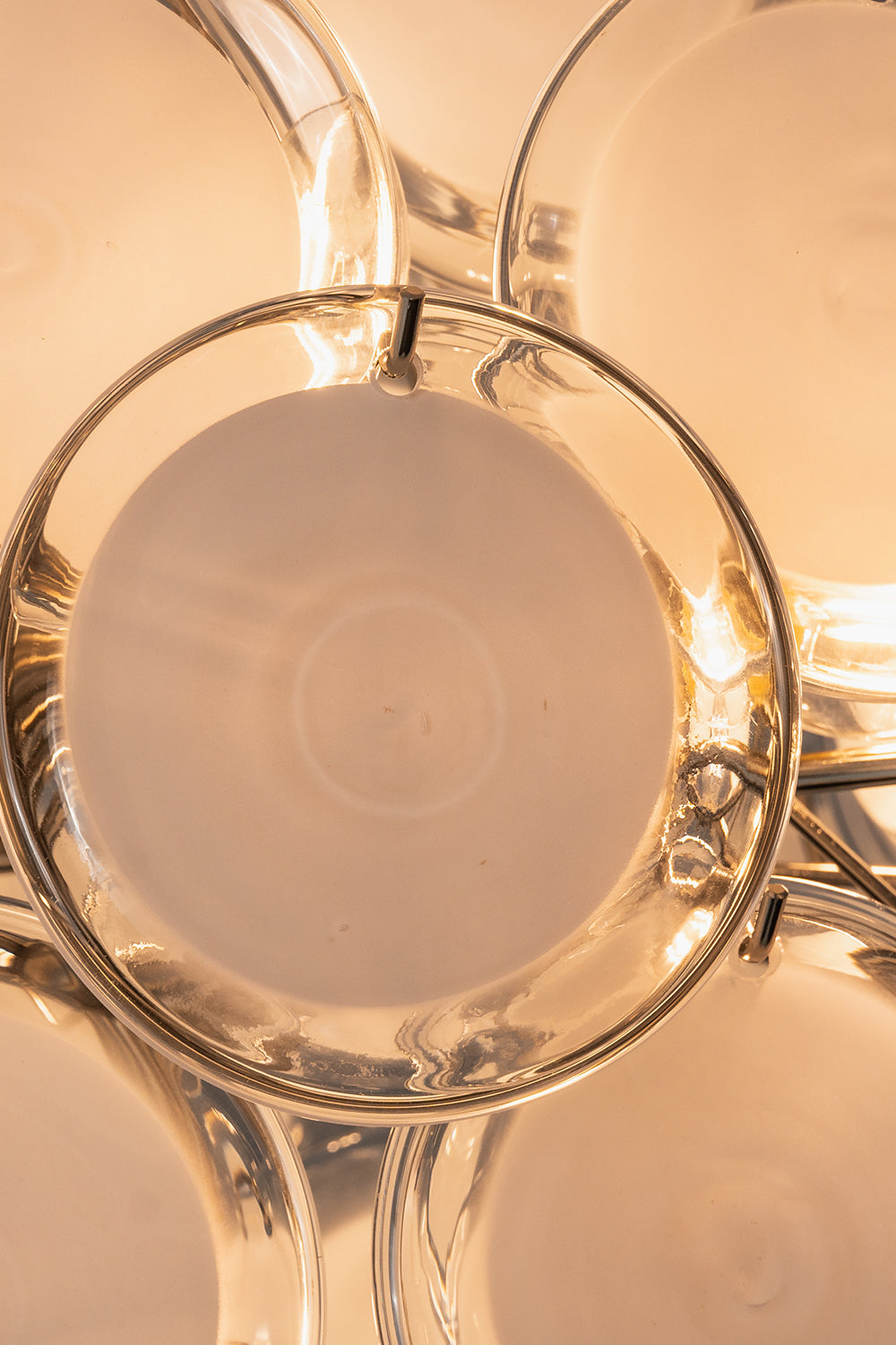 Mirella Circular Glass Pane Ceiling Light | Illuminated Detail | Close-up macro view of a single glowing white circular glass disc panel radiating soft warm light from the internal bulb | Detail shot | Samu Lamp