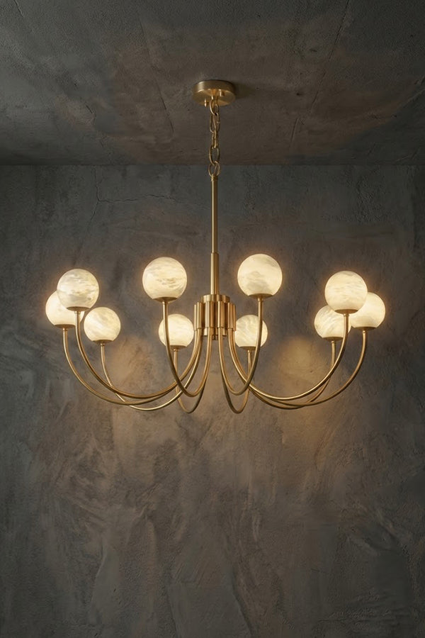 Lit 10-light brass chandelier | Alabaster, Brass | Slightly angled view against a concrete-style background | Samu Lamp