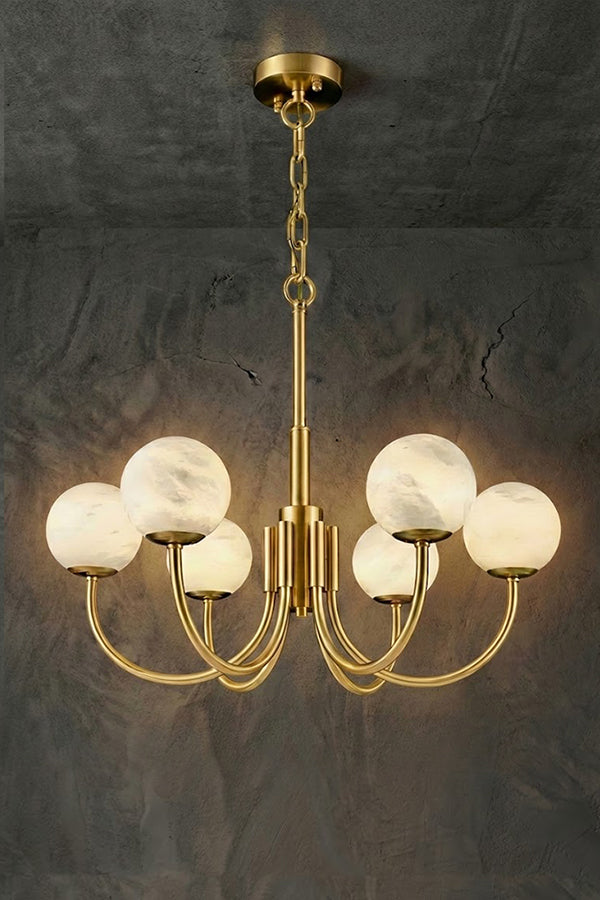 Lit 6-light brass chandelier | Alabaster, Brass | Slightly angled view against a concrete-style background | Samu Lamp