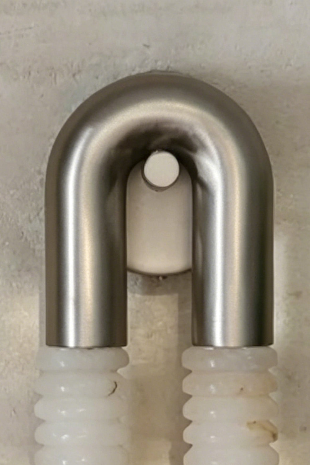 Monolith Arc Alabaster Wall Lamp | Alabaster, Metal | Close-up focus on the brushed metal U-arc and minimalist mounting point | Detail shot | Samu Lamp