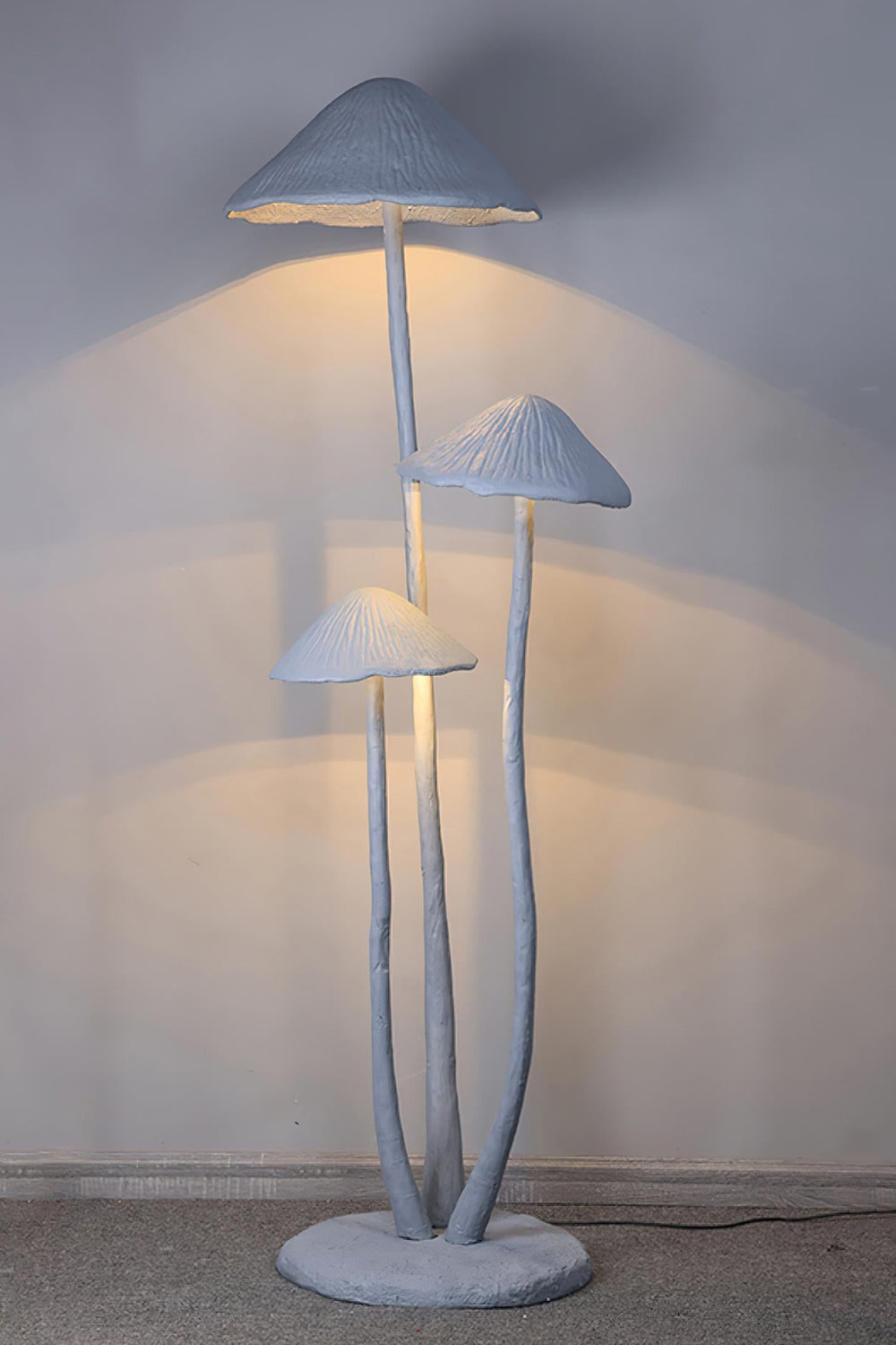 Mycena Cluster Resin Mushroom Floor Lamp | Resin, Metal | Full vertical view of the illuminated multi-mushroom lamp projecting a warm comforting downward light on a plain wall | Samu Lamp