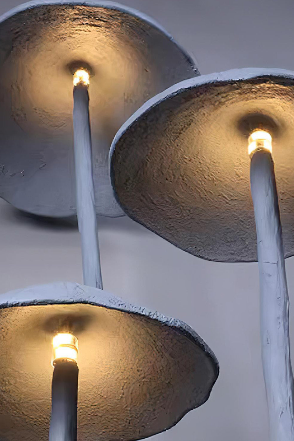 Mycena Cluster Resin Mushroom Floor Lamp | Resin, Metal | Upward close-up perspective of the three illuminated caps from below showing the warm yellow light bulb glow | Detail shot | Samu Lamp