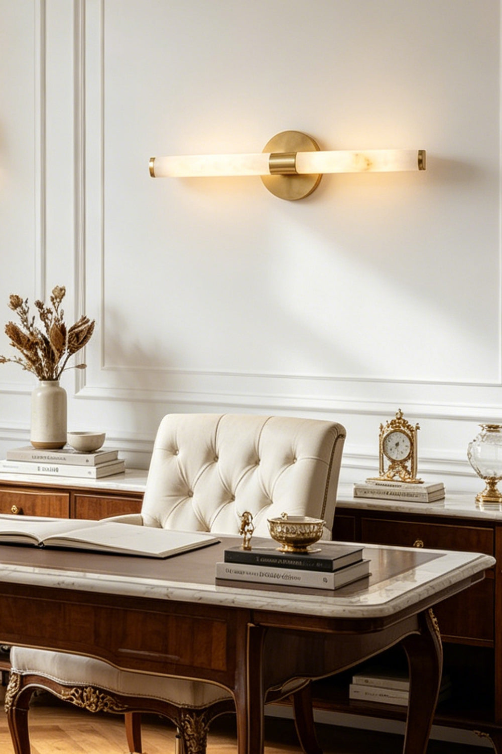 Nerida Linear Alabaster Wall Sconce | Alabaster, Brass | Staged interior view of the fully lit linear stone light fixture casting a warm halo over a traditional desk and a tufted leather chair | Samu Lamp