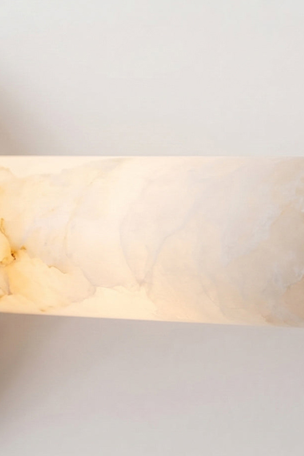 Nerida Linear Alabaster Wall Sconce | Alabaster, Brass | Macro view of the fully illuminated translucent natural white alabaster stone cylinder showcasing its rich cloudy mineral veining | Detail shot | Samu Lamp