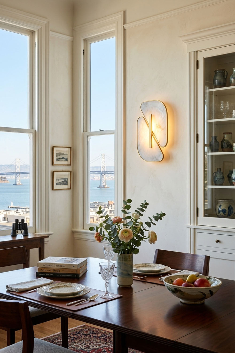 Nerine Overlapping Alabaster Wall Lamp illuminating a stylish dining area with a view.